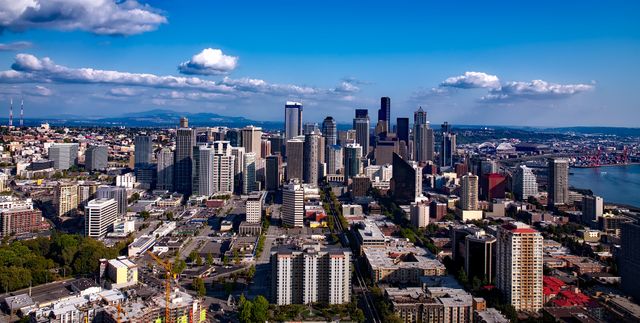 Aerial view of downtown Seattle showcasing iconic skyscrapers and the city's waterfront on a sunny day. Ideal for use in travel brochures, websites promoting Seattle tourism, real estate advertisements, and urban development presentations.