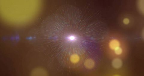 Radiant golden starburst emitting light with bokeh glow and blue lens flare on brown
