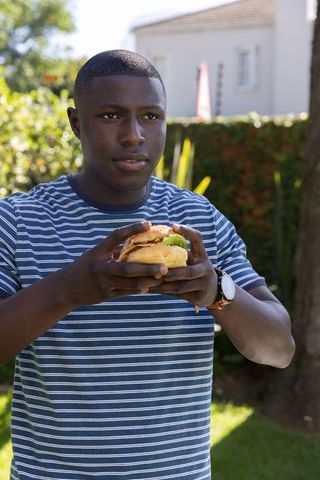 Man Relaxation Enjoying Burger in Backyard during Sunny Day