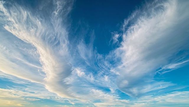 Wings of dawn: cirrus plumes fanning across expansive blue morning sky