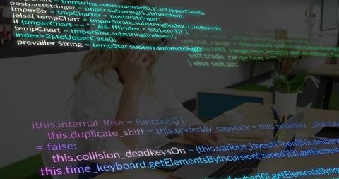 White-hoodie woman calling while coding overlay on laptop in modern coworking workspace