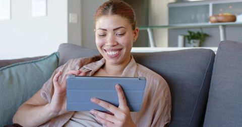 Smiling woman using tablet on sofa for budgeting and personal finance planning