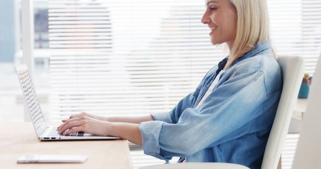 Smiling Woman Working on Laptop at Modern Office Desk - Download Free Stock Images Pikwizard.com