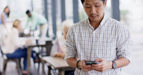 Asian Man Using Smartphone in Modern Office Setting