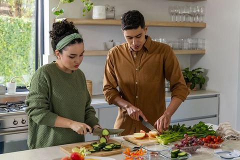 Couple preparing healthy meal together on sunlit modern kitchen island with fresh produce
