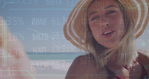 Woman in Sun Hat Enjoying Beach with Financial Data Overlay