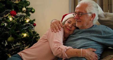 Senior Couple Embracing by Christmas Tree Celebrating Holiday