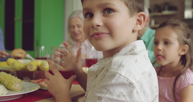 Happy Boy Holding Glass with Family during Dinner in Kitchen - Download Free Stock Images Pikwizard.com