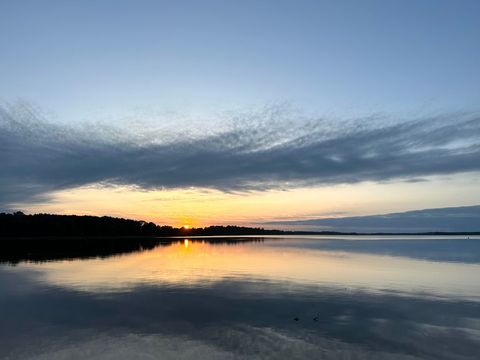 Serene beach sunrise across calm lake reflecting vibrant sky