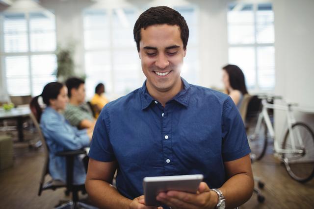 Man smiling while using a digital tablet in a modern office environment. Ideal for illustrating concepts of technology in the workplace, business productivity, and modern office settings. Suitable for use in corporate websites, business presentations, and marketing materials.