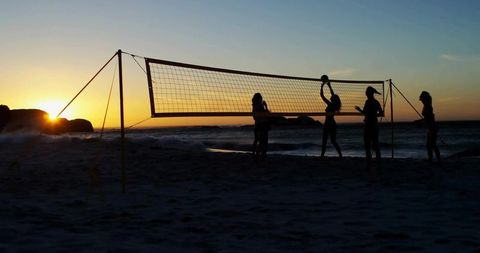 Women Playing Beach Volleyball at Sunset Silhouette