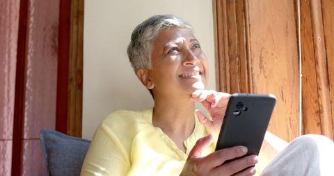 Senior Woman Enjoying Smartphone at Home Near Sunny Window