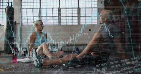 Fitness Partners Sitting on Gym Floor Analyzing Stock Market Chart Overlay for Business