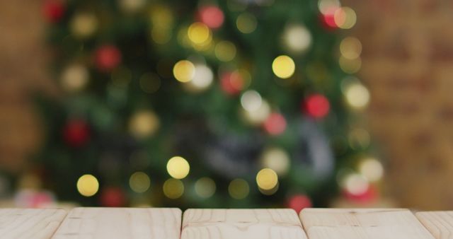 Festive and warm Christmas-themed background featuring a blurred Christmas tree with glowing lights and a wooden surface in the foreground. Ideal for holiday greetings, seasonal promotions, and backgrounds for festive advertisements.