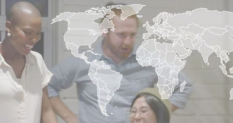 Smiling colleagues collaborating over laptop with translucent world map overlay