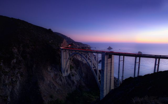 Majestic bridge spanning rugged coastline at sunset overlooking Pacific Ocean. Excellent for travel blogs, tourism advertisements, scenic wallpapers, architectural showcases, and nature photography portfolios.