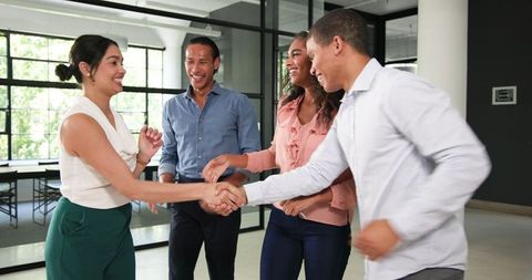 Diverse team celebrating with red ribbon in office