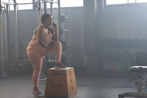 African american woman pausing mid-workout on plyometric box in industrial gym