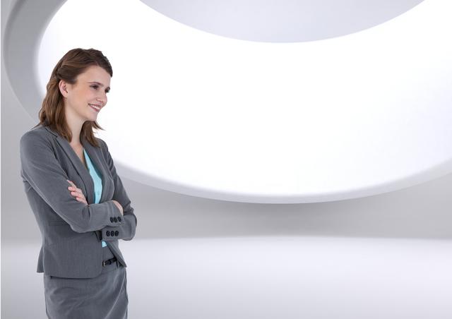 This image features a professional businesswoman confidently standing with folded arms in a modern, minimalist, bright space with curved architectural elements. It is ideal for corporate, business, and professional themes, illustrating confidence, modern workplace environments, leadership, and business success. This can be used in websites, presentations, and marketing materials to convey professionalism and contemporary office settings.