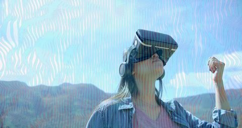 Exploring virtual worlds outdoors wearing vr headset and headphones against mountain horizon