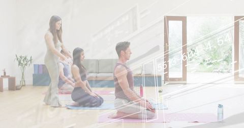 Instructor guiding kneeling yoga students in bright studio for mindfulness and balance