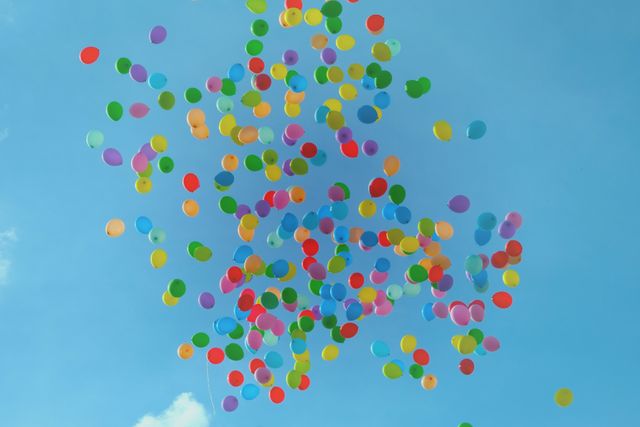 Multiple colorful balloons floating against blue sky. party, celebration and event concept