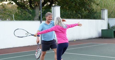 Senior Couple Embracing at Tennis Court Celebrating