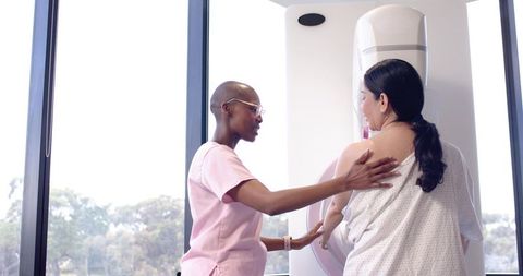 African American technologist guiding woman during mammography screening and positioning