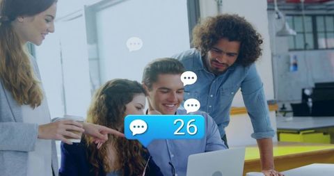 Team Collaborating Around Laptop with 26 Message Notification Bubble in Modern Coworking Office