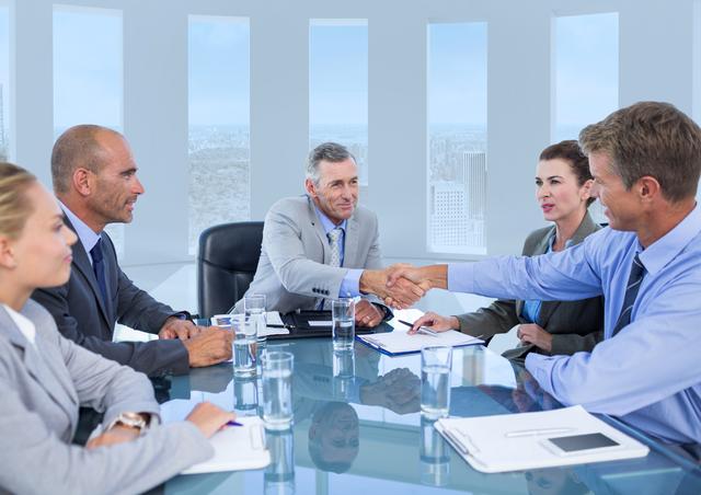 Businessmen shaking hands in a modern conference room, symbolizing successful agreement and partnership. Ideal for use in business-related content, corporate presentations, teamwork and collaboration themes, negotiation and deal-making visuals, and professional success stories.