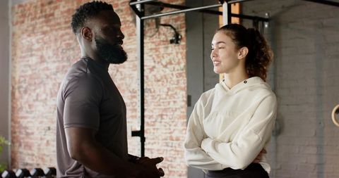 Personal trainer guiding client inside industrial-style gym