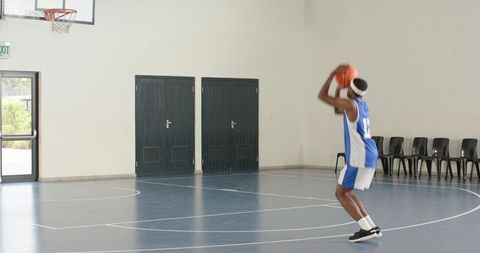 African american basketball player practicing shooting in gym