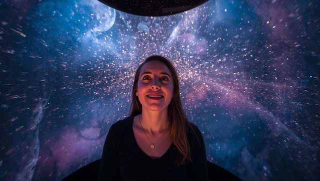 Woman gazing into immersive planetarium dome with dazzling stars, nebula and crescent moon