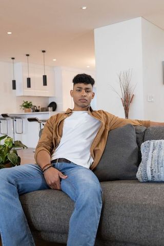 Young man sitting relaxed on gray sofa in modern minimalist living room