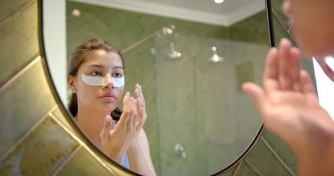 Teen girl applying under eye masks for skincare in bathroom