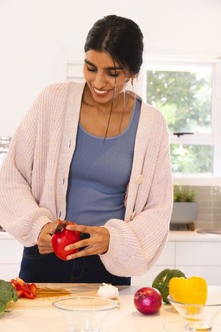 Smiling Woman Preparing Meal in Modern Kitchen with Fresh Vegetables