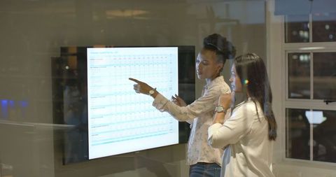 Businesswomen Analyzing Sales Data on Digital Screen in Office