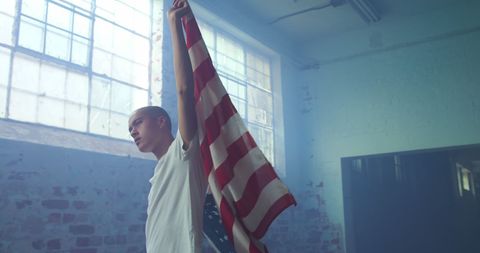 Contemplative Young Man Holding American Flag in Dimly Lit Room - Download Free Stock Images Pikwizard.com