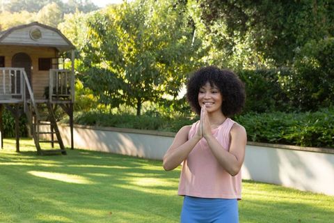 African american woman practicing mindfulness and gratitude on sunlit lawn by playhouse