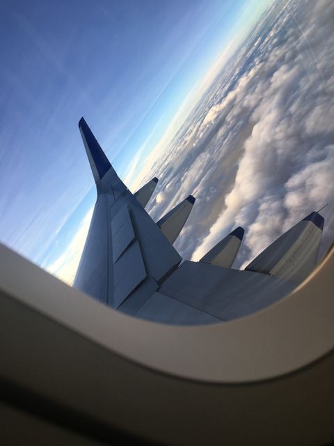 This photo captures the view from an airplane window, showcasing the aircraft wing and a stunning panorama of clouds and blue sky. Perfect for travel blogs, airline promotions, aviation articles, and travel agencies highlighting the experience of air travel.