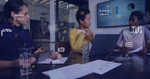 Businesswomen discussing data charts in collaborative office meeting with laptop and tablet