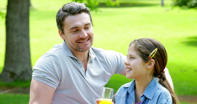 Father and daughter enjoy quality time together in a sunny park. Good for concepts related to family bonding, parenting, happiness, and outdoor activities. Ideal for advertisements, lifestyle blogs, and parenting websites.