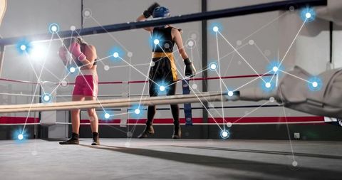 Female boxers sparring in boxing ring with futuristic digital data network overlay