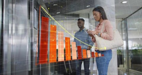 Businesswoman tapping smartphone while viewing holographic declining bar graph in lobby