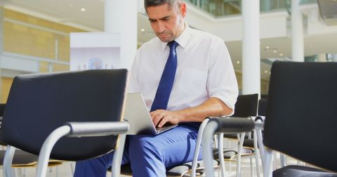 Focused Businessman Typing on Laptop in Modern Conference Hall