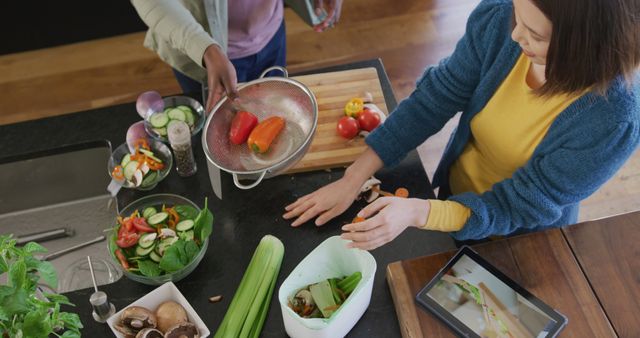 High angle image of diverse couple preparing food using tablet and composting vegetables in kitchen. Domestic life, communication, togetherness, health, happiness and inclusivity concept.