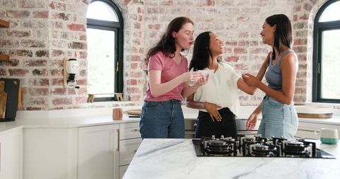 Excited Female Friends Celebrating Special News in Bright Kitchen