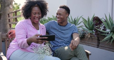 Happy Couple Seated on Bench Taking Outdoor Selfie Together