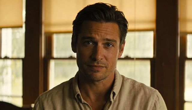Contemplative man in beige shirt with warm backlit windows and cozy interior light