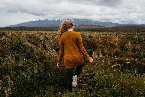 Woman Exploring Wild Field with Mountains in Background